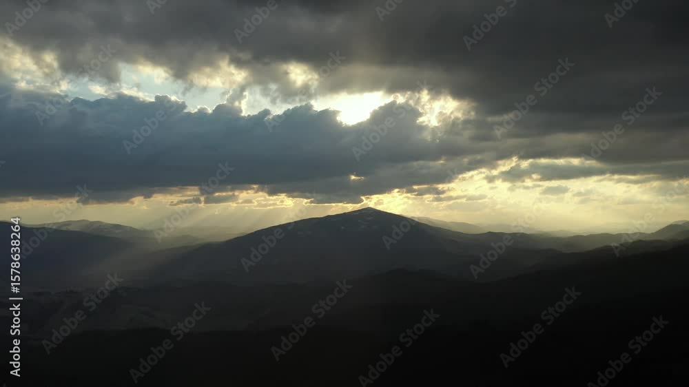 Aerial view of majestic mountain landscapes under a dramatic cloudy sky. Serene and powerful nature scene captured from drone, showcasing untouched wilderness and moody weather atmosphere. Aerial view of majestic mountain landscapes under a dramatic cloudy sky. Serene and powerful nature scene captured from drone, showcasing untouched wilderness and moody weather atmosphere.