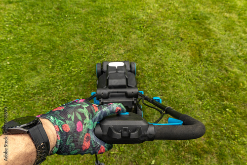 Wallpaper Mural A gardener wearing colorful protective gloves mows the lawn, a view of the mower's basket from the mower's perspective, Torontodigital.ca