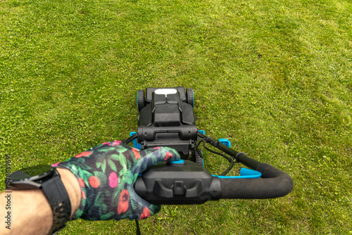 Wallpaper Mural A gardener wearing colorful protective gloves mows the lawn, a view of the mower's basket from the mower's perspective, Torontodigital.ca