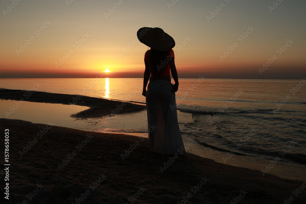 Fototapeta premium woman walking on the beach at sunrise