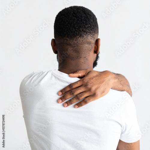 Person with short curly hairstyle and dark skin shows hand on their shoulder, expressing concern about mental health and physical discomfort