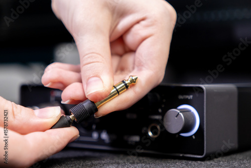 Foto Close-up of human hands precisely plugging a shiny gold-tipped audio jack into a