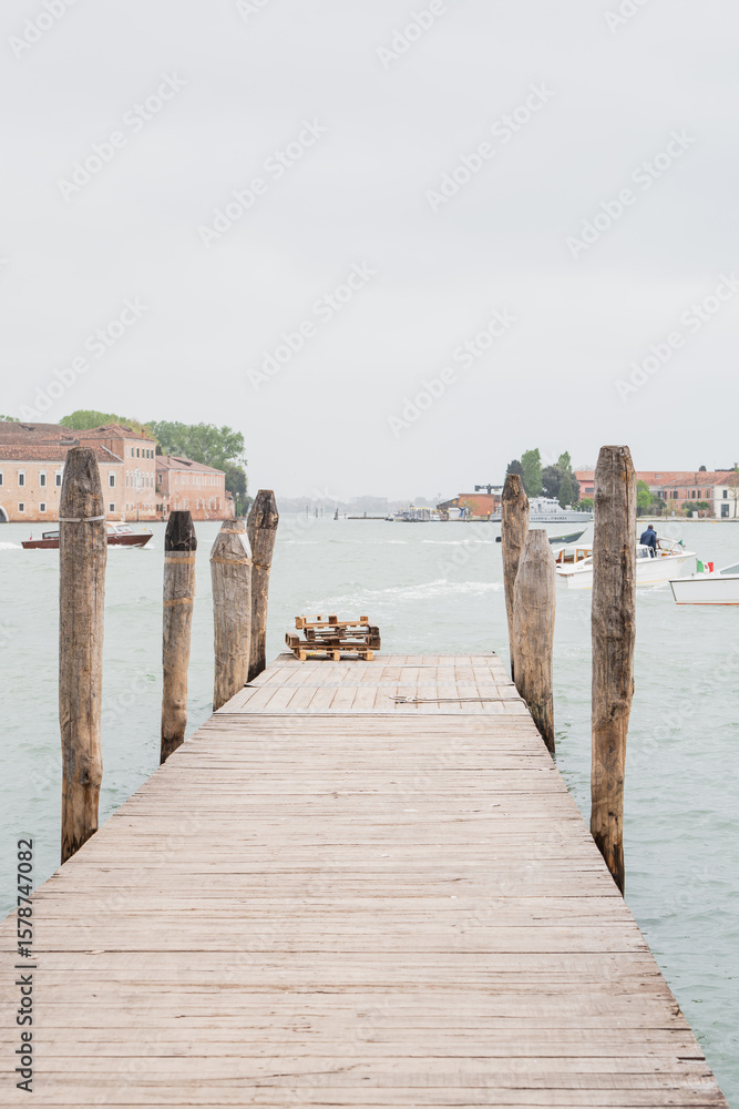 Fototapeta premium Wooden pier extending into a serene lagoon on a cloudy day