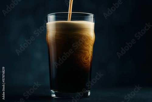 Dark nitro coffee pour creating satiny cascades and creamy wave patterns in pint glass