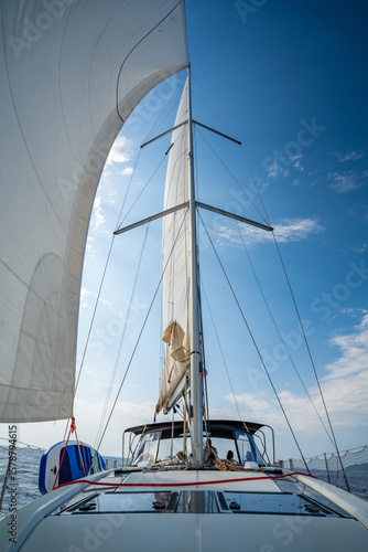 White sails filled with wind, seen from the bow of a sailing yacht near Croatia. Freedom, clean energy, adventure and mindful travel on the open sea.