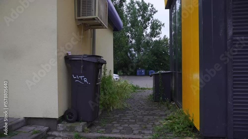 A trash bin in an alley, with a parking lot in the background, offering a glimpse into the urban landscape and everyday life 
