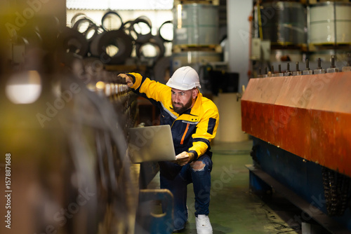 Laptop computer : blue collar working production line : Caucasian man engineer worker working control sheet metal roof tile roll forming machine at metal sheet profiling factory. Industrial production