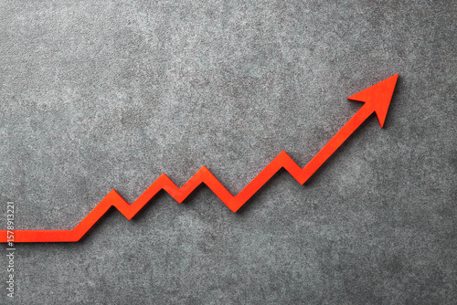 Fotografía A red upward arrow on a stone background, symbolizing growth or rising trends in finance or economics