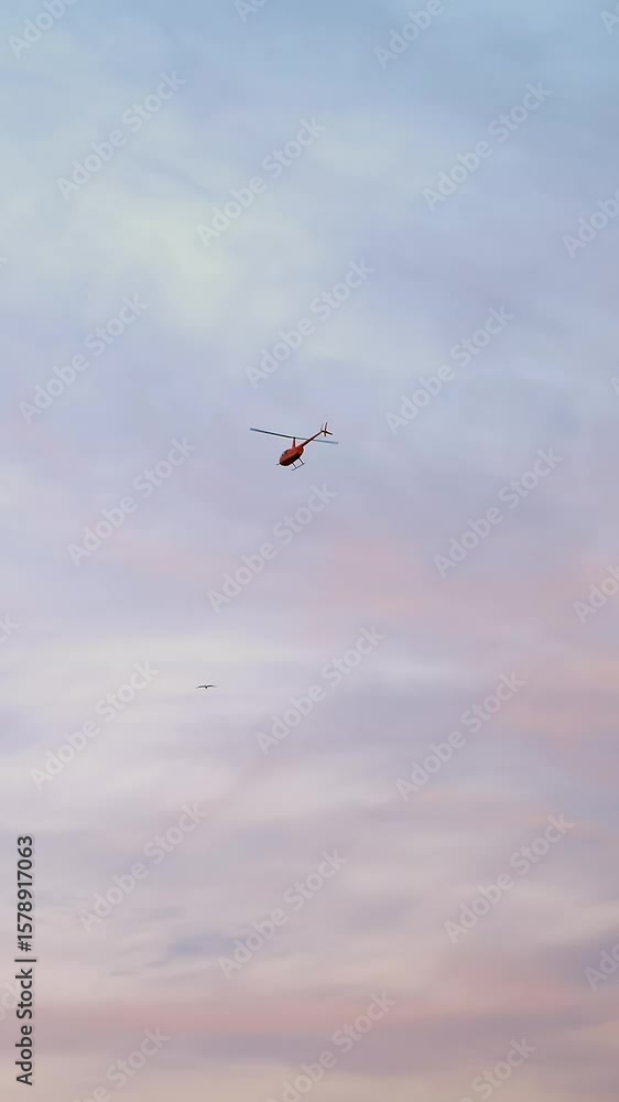 A red helicopter flies in the sky. against the blue sky, clouds, and pink sunset, A red helicopter flies in the sky. against the blue sky, clouds, and pink sunset,