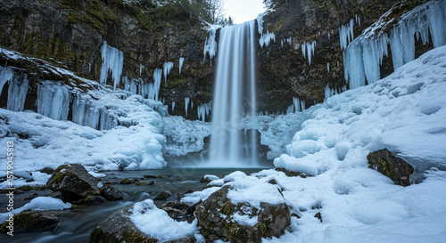 Cascading waterfall in a winter setting flanked by rock formations and icicles