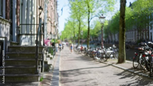 Wallpaper Mural Blurred view of amsterdam canal street with bicycles, trees, and people walking, capturing the essence of a sunny day in the netherlands. Torontodigital.ca