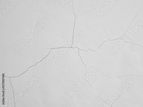 Background of hairline crack on white painted concrete wall. Fine cracks on the wall are caused by temperature changes, material shrinkage, structural movement, or poor quality building materials.