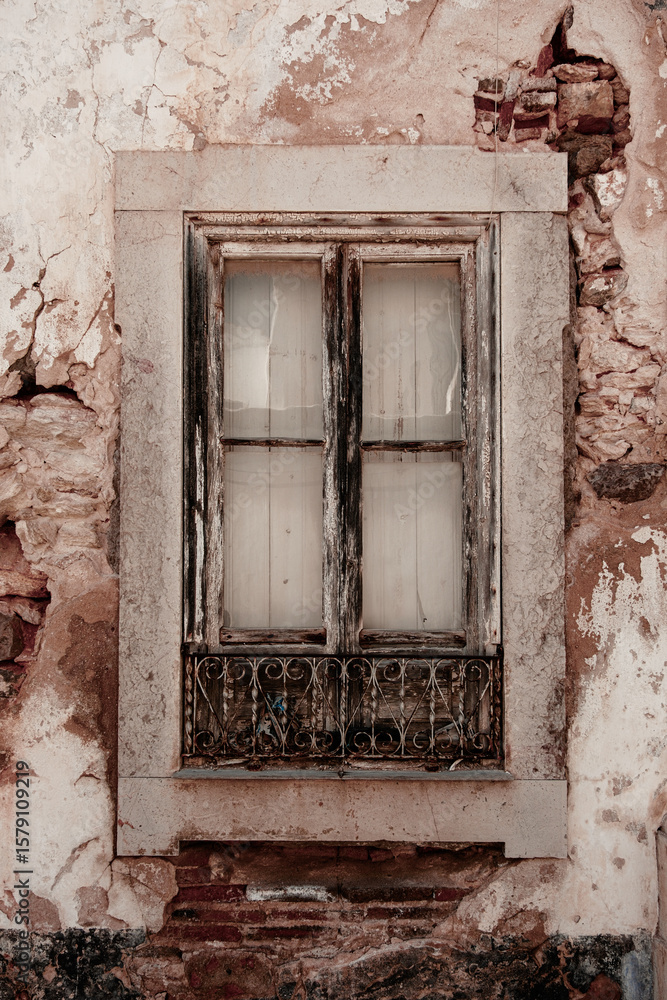 Old window in very old wall with stonework and broken plaster in Tavira, Portugal Old window in very old wall with stonework and broken plaster in Tavira, Portugal