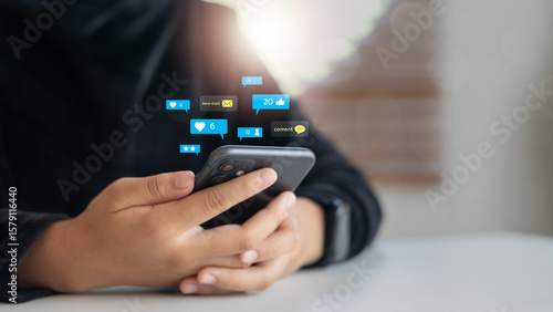 Quadro su tela Close-up of a hand holding a smartphone with floating social media notifications including likes, comments, messages, and user reactions
