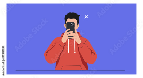 Young man in a red hoodie takes a photo with his smartphone against a blue backdrop, capturing a modern lifestyle moment with a digital device