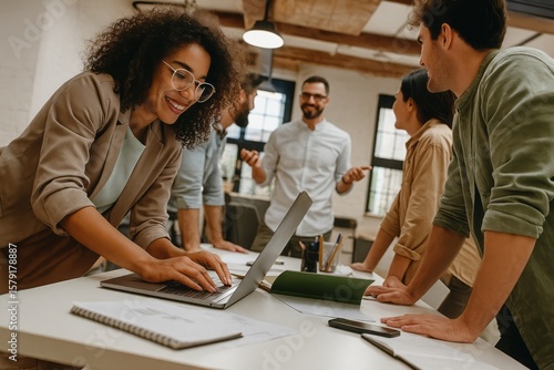 Focused professional woman collaborating with diverse colleagues in a modern office, demonstrating teamwork and effective communication during project development with a smiling expression.