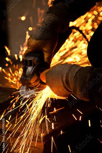 Worker working in industry or factory is holding a cutting stone or grinding stone and sparks are coming out of the metal