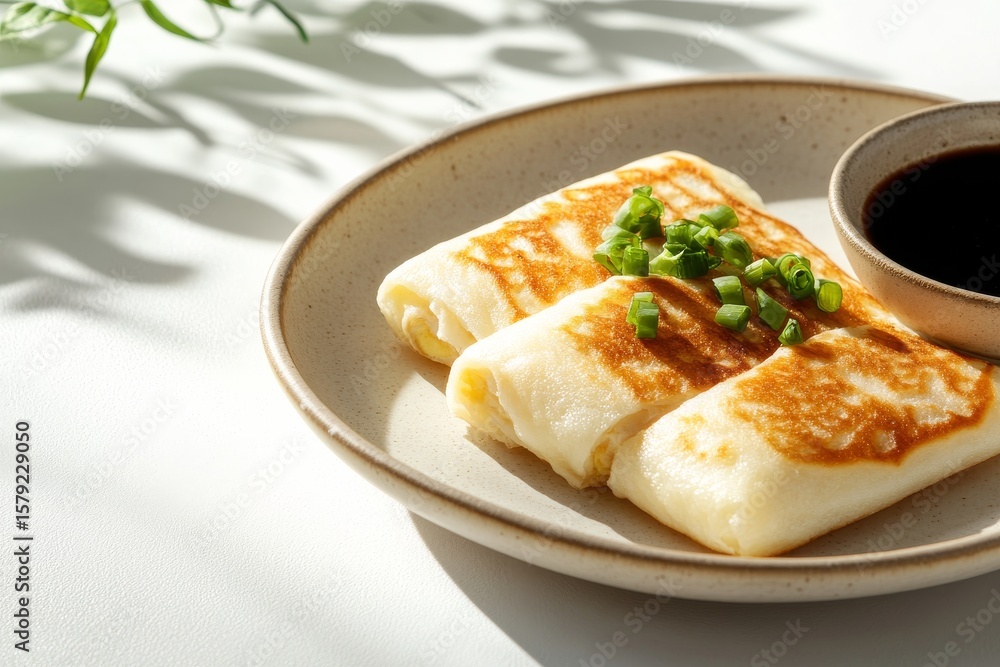 Traditional taiwanese breakfast dan bing with scallions and soy sauce on a plate Traditional taiwanese breakfast dan bing with scallions and soy sauce on a plate