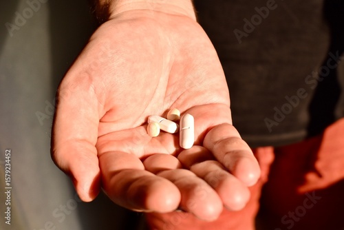 Several pills in a man's hand. Concept of medicine, treatment, and personal healthcare.