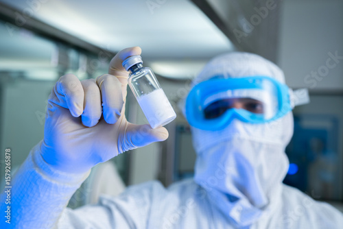 lyophilised injection isolated. isolated vaccine vial injection in hand. background of machine manufacturing a lot of injections in glass ampoule vial in a healthcare pharmaceutical factory process