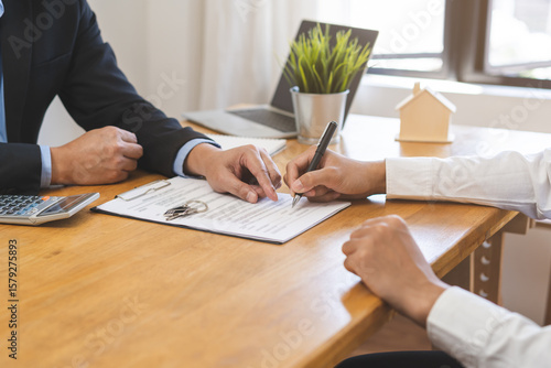 Asian landlord, realtor man pointing on paper for sign signature contract with tenant rental or client, realtor purchase, buyer home or apartment, agreement mortgage, property lease agent concept. © KMPZZZ