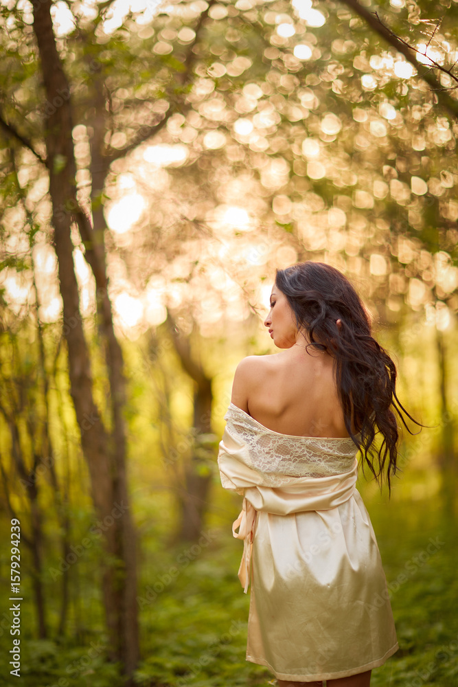 A woman in a white dress stands in an autumn forest. She is naked and hugs herself with her arms. A woman in a white dress stands in an autumn forest. She is naked and hugs herself with her arms.