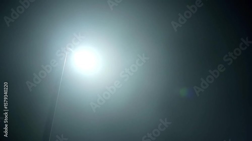 Bright streetlight illuminating foggy road at night  