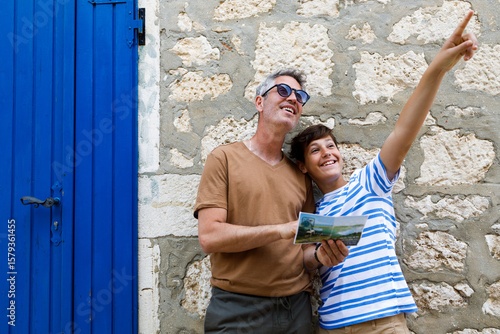 A father and son on a sightseeing trip in Rovinj, Croatia. . They are holding a map. Both appear cheerful and curious, enjoying their time exploring the city together.	
