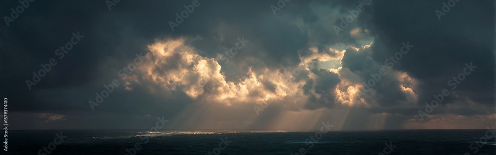 Fototapeta premium Dramatic ocean panorama showcasing sunlight filtering through stormy clouds creating a surreal