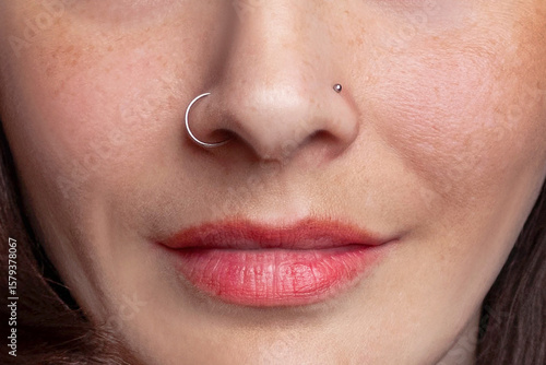Nose piercing. Nose wing ring and clove earring. Macro shot. 