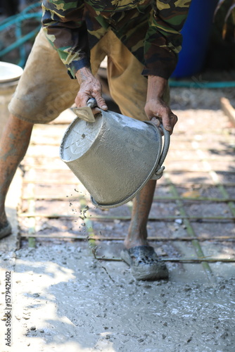 Cement pouring on steel rebar grid during construction, cement pouring close-up with wet texture in daylight, cement pouring on reinforced foundation floor