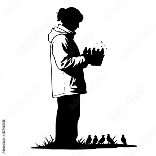 Young person feeding birds while standing on grass in silhouette  
