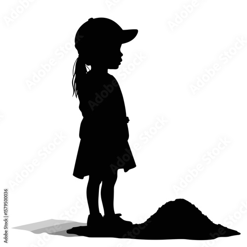 Silhouette of child standing beside pile of sand in profile view  