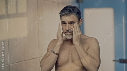 Fotografía Mature adult man applying cosmetics in bathroom mirror in morning