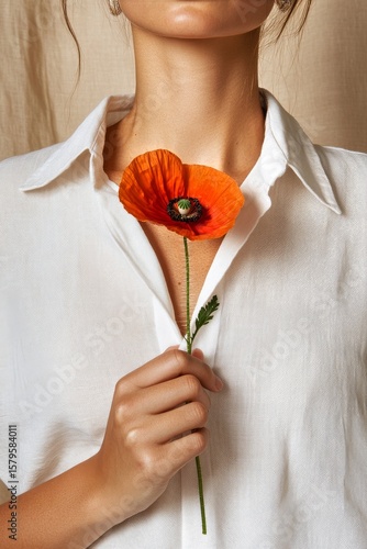 Woman Holding Vibrant Orange Flower While Dressed in a White Shirt Indoors
