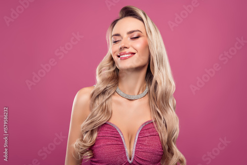 Stunning blonde woman in pink dress with jewelry and glamorous look on a pink background, portraying style and beauty