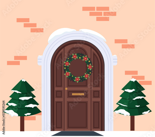 Fragment of the house facade with a door and a Christmas wreath. Christmas trees at the entrance. Brick facade. Festive atmosphere and anticipation of Christmas and New Year. Winter festive decoration