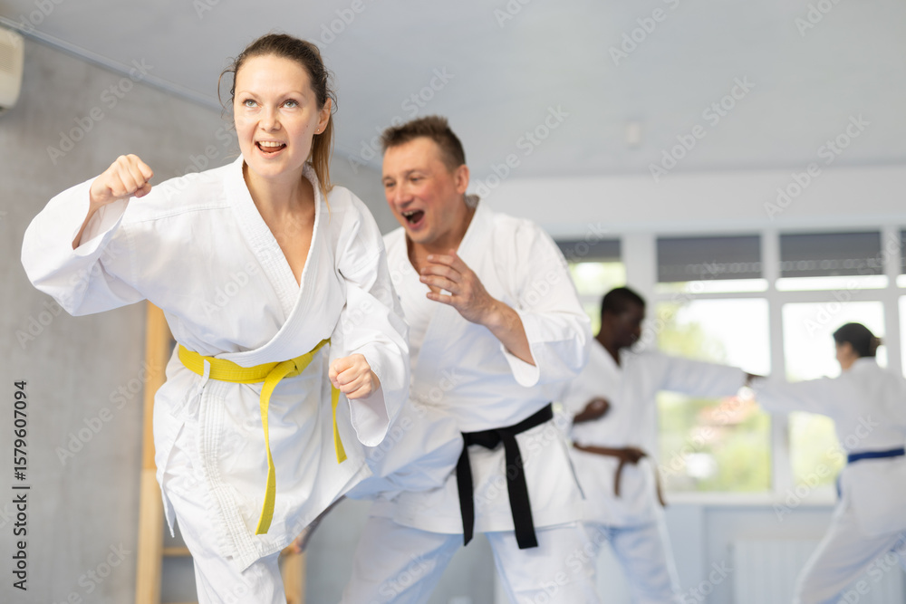 Obraz premium Adult man and adult woman judokas practicing judo technique in group in gym
