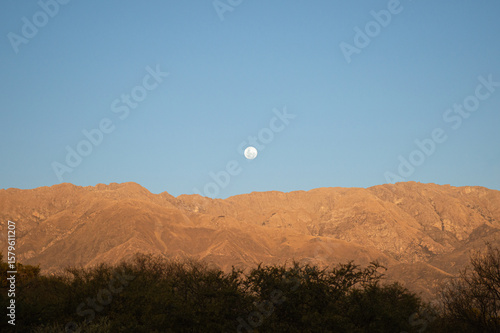 full moon over orange mountains at sunset