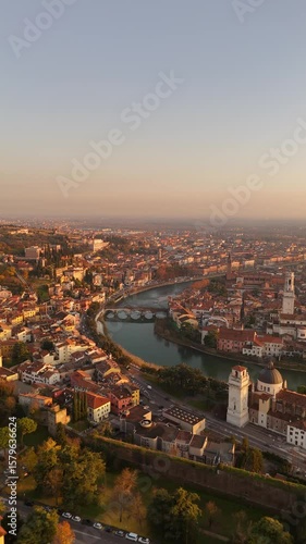 Wallpaper Mural Vertical drone flyover above Verona, Italy at golden hour. Sunset light on colorful classic buildings, historic architecture, Adige River reflections, old town streets, and rooftops. cinematic view Torontodigital.ca