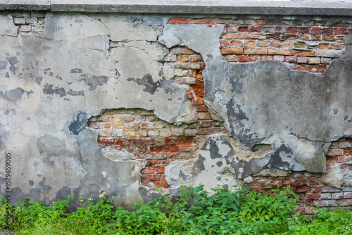 Fotografi Crumbling brick wall with damaged plaster revealing layered weathering patterns