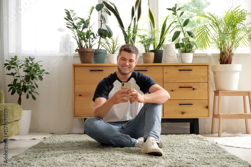 Young handsome gardener usi...