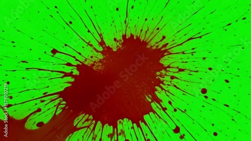 A blood splatter effect with dripping trails on a vibrant green screen background for visual effects use