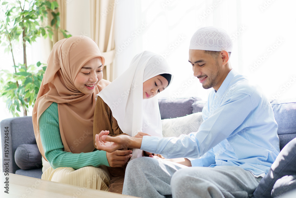 Obraz premium Happy Asian muslim family sits together in a cozy living room.
