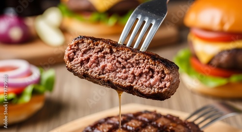 Juicy burger patty on a fork with burgers in background