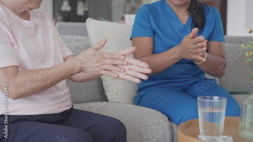 Asian health care worker giving elderly woman physiotherapy at home, home nurse, home care service concept

