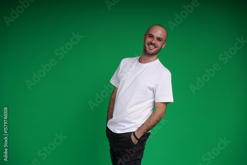 Young man with a variety of emotions, wearing a white t-shirt standing against a green background. Studio shot with copy space.
