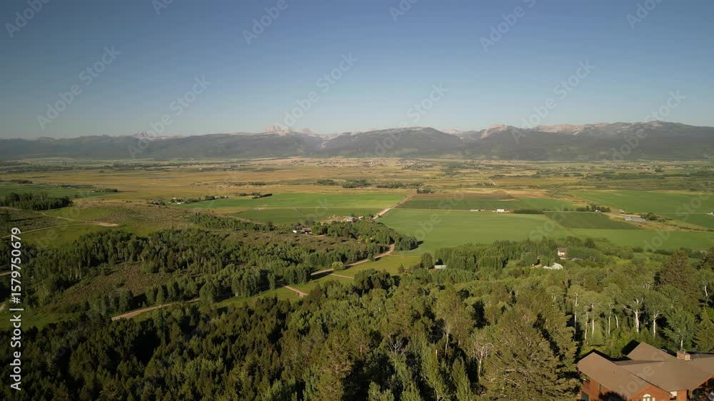 Aerial above forested mountain homes in Victor Idaho in summertime with view of Tetons