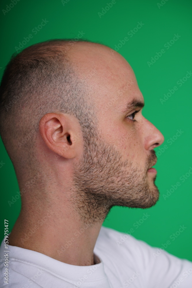 Obraz premium young man wearing a white t-shirt standing against a green background. Studio shot with copy space.