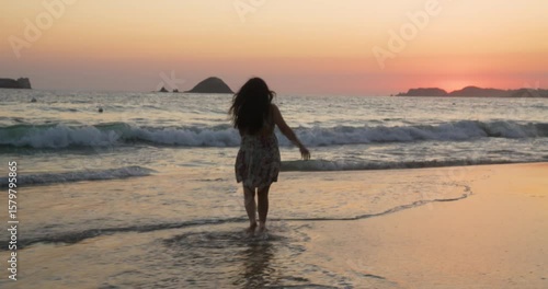 Woman enjoys the beach at sunset in Zihuatanejo in slowmotion